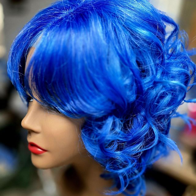Vivid blue curled wig unit with a side-swept bang