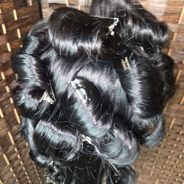 Black hair pinned in a roller set before styling